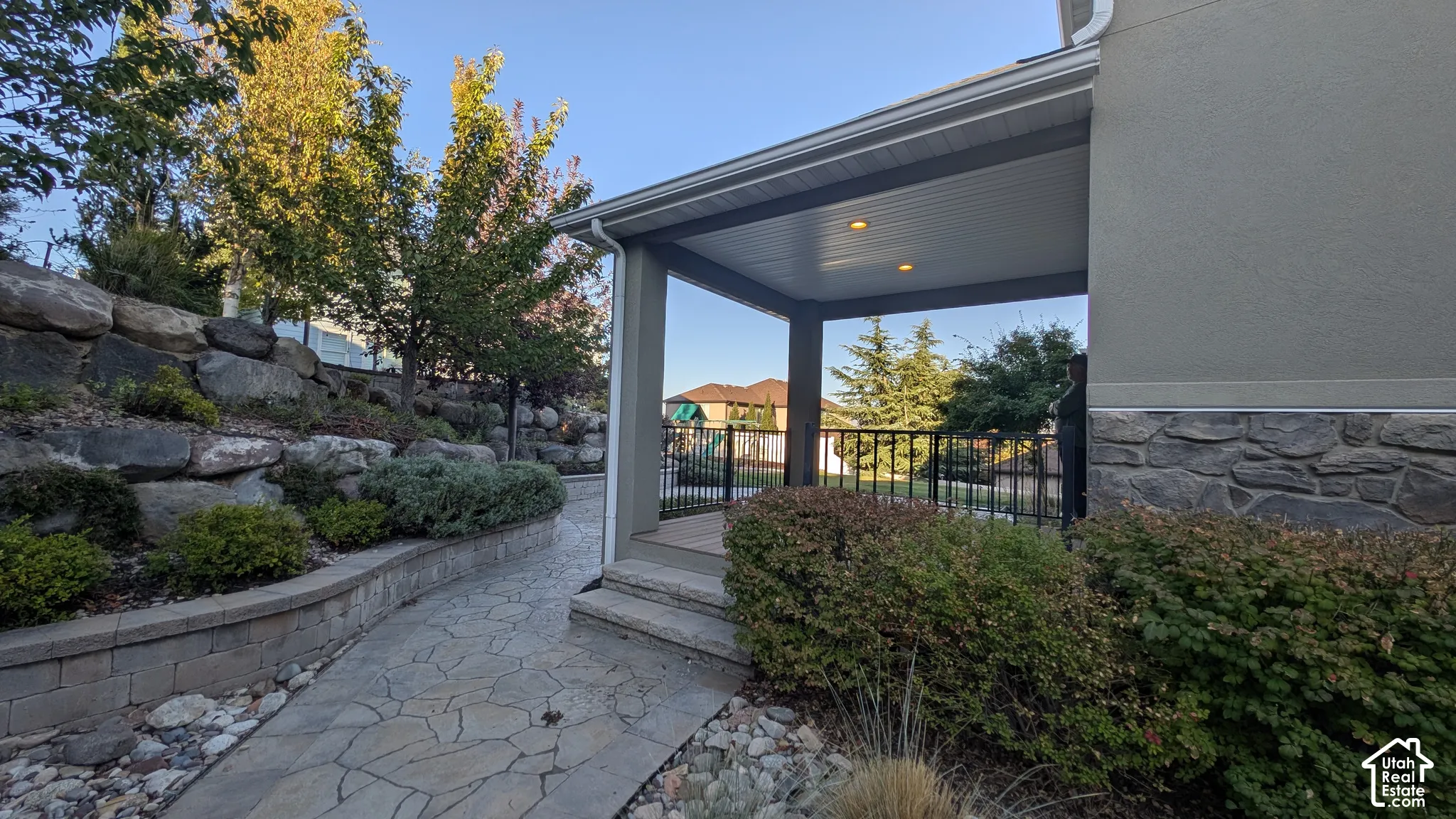 Covered patio with recessed lighting, stone veneer siding, and a flagstone pathway