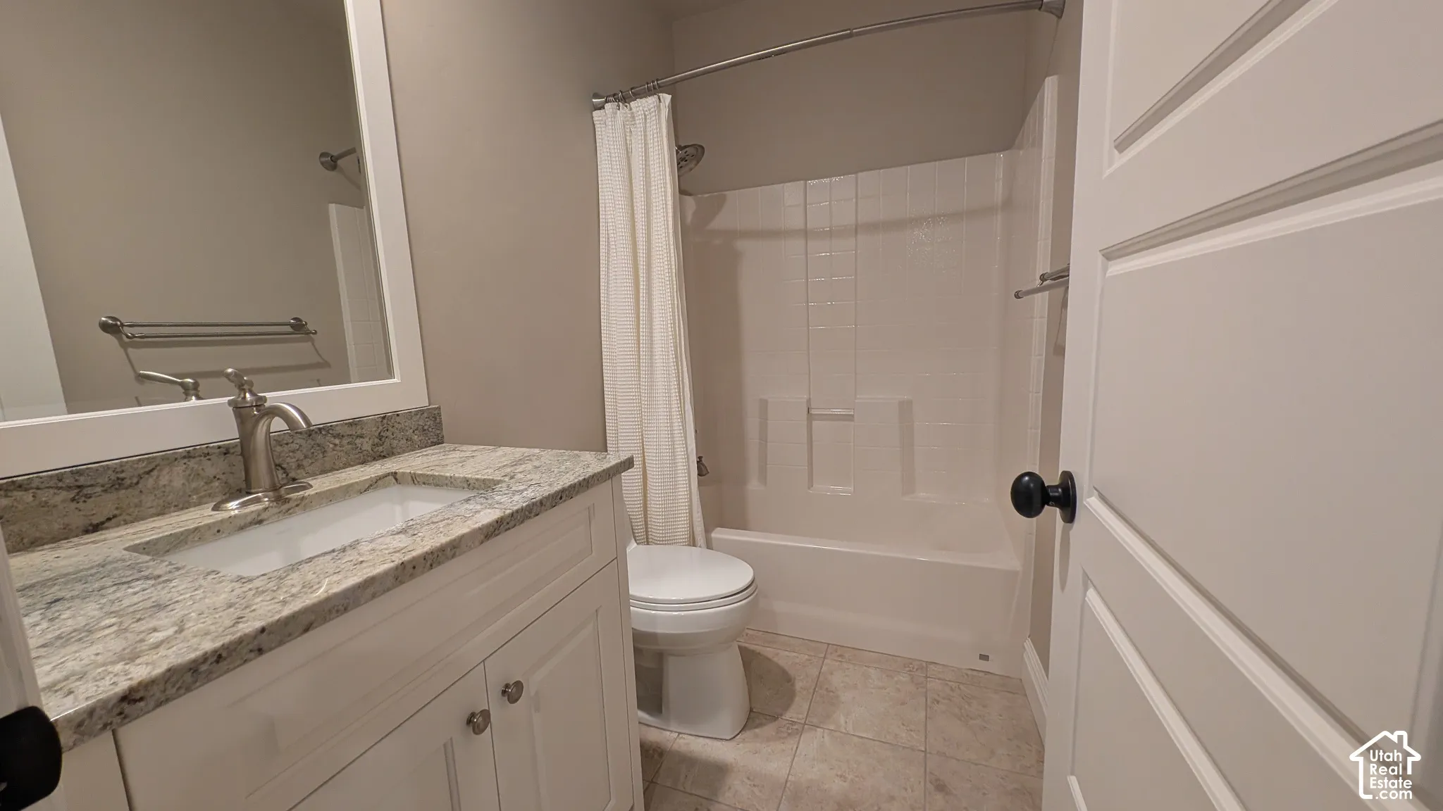 Bathroom featuring a white vanity with a granite-style countertop, undermount sink, and a framed mirror