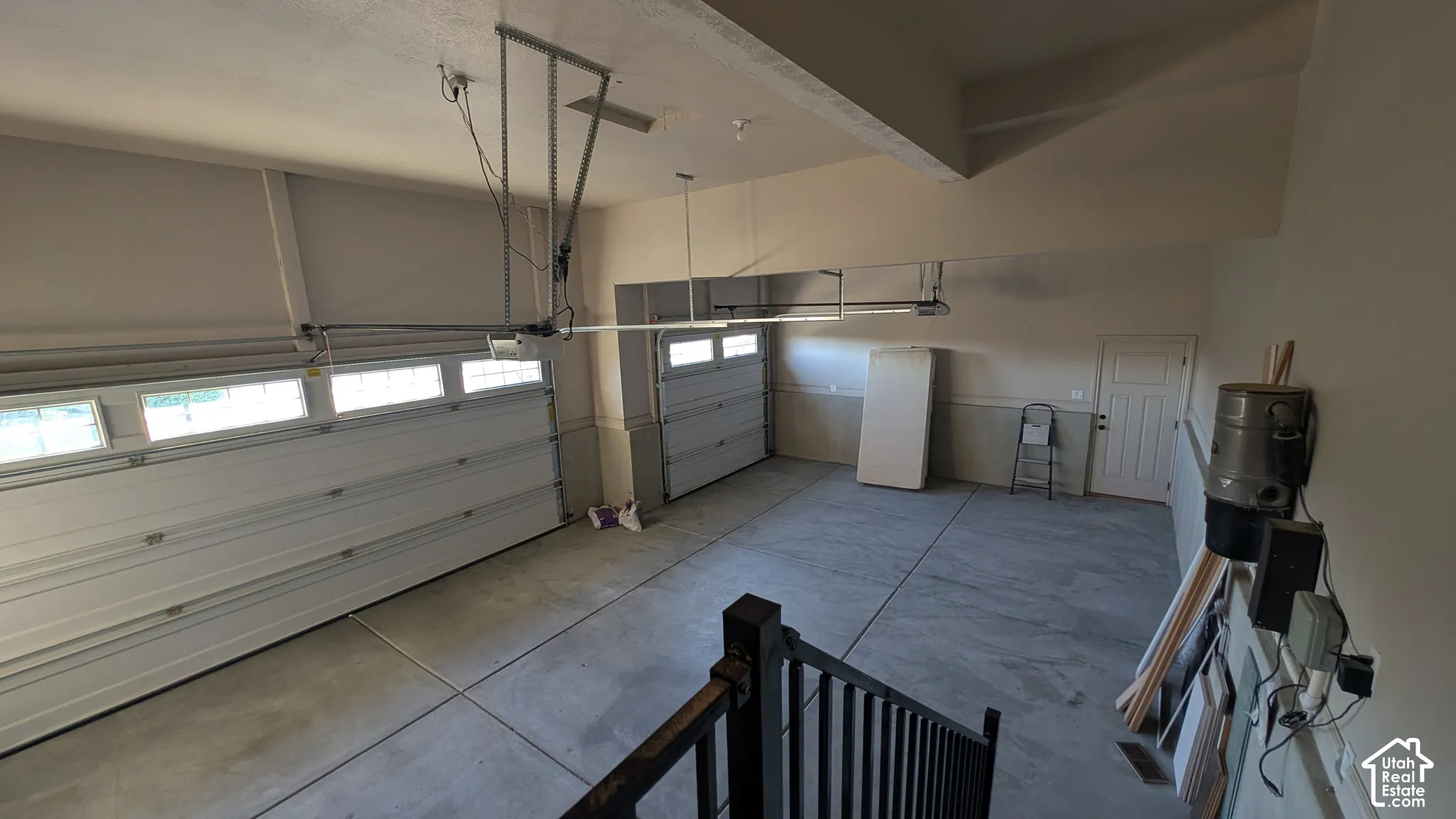Three car garage with concrete flooring, two overhead garage doors, and an interior access door, storage cabinets, central vac