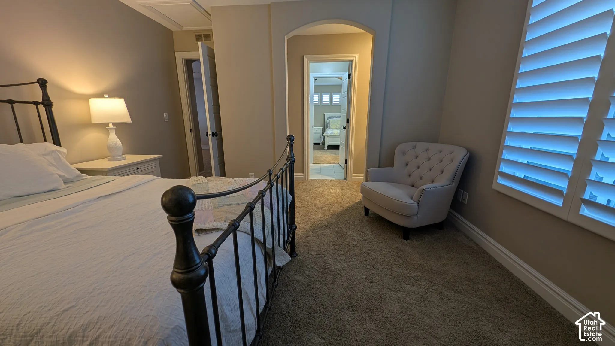 Charming spacious bedroom sharing jack and jill bathroom. Soft carpeted flooring, neutral wall paint, white trim, and two paneled closet doors. Archway entry, plantation shutters, and soft-pile carpeting