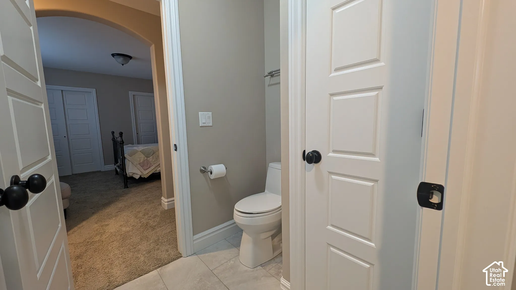 Jack and Jill bathroom with Tiled flooring in bathroom with white baseboards and toilet