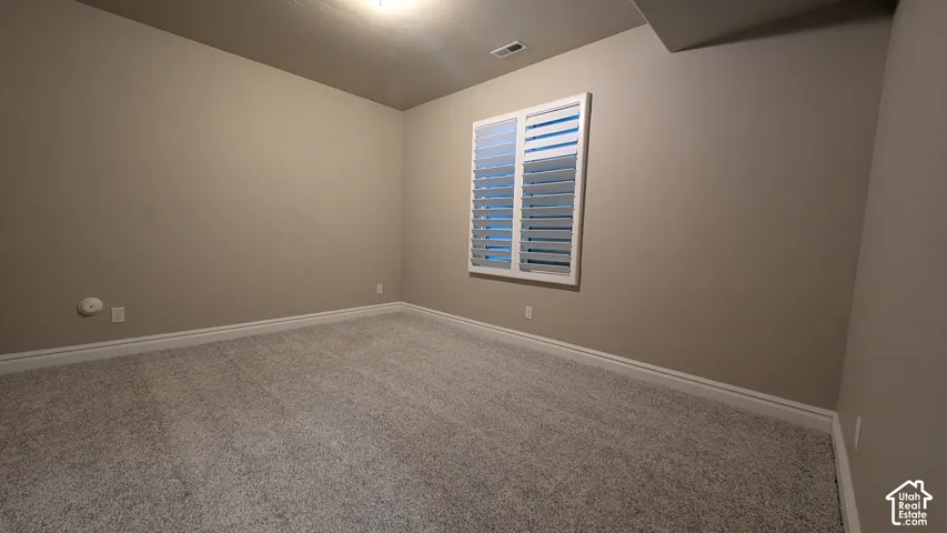 Plush carpeting, neutral wall tones, and elegant window shutters