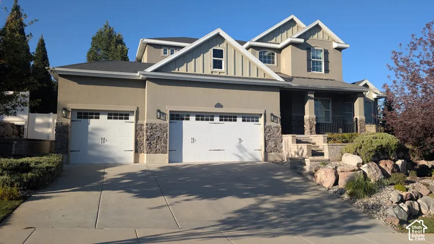 Stucco and stone facade, two-car garage, covered porch entry, and tiered landscaping