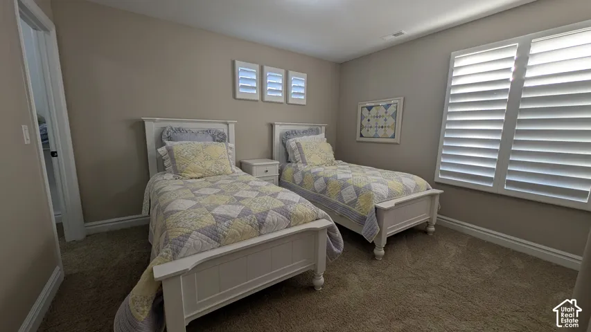 spacious bedroom with Carpeted flooring, neutral wall tones, and white plantation shutters