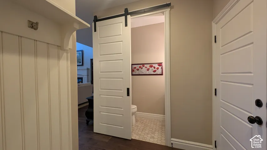Wood-finish flooring leading to a white paneled barn door half bath