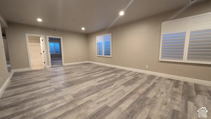 Other view of large family room with Expansive room featuring wood-finish flooring, recessed lighting, and windows with white plantation shutters