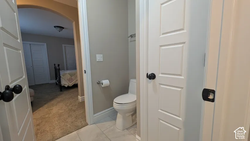 Jack and Jill bathroom with Tiled flooring in bathroom with white baseboards and toilet