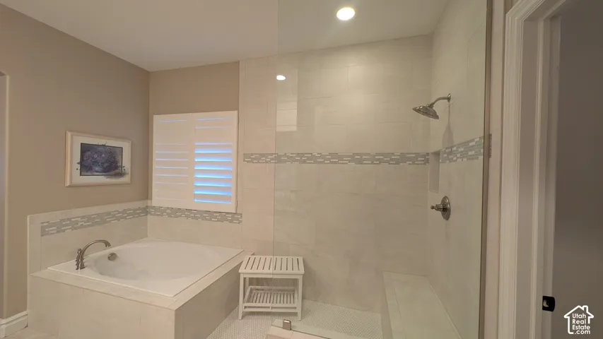Soaking tub with bronze-finish fixtures, tile surround, and plantation shutters. Independent shower and bath, with private toilet areas