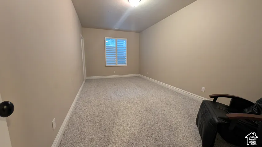 Neutral-toned walls, carpeted flooring, and a window with white louvered shutters