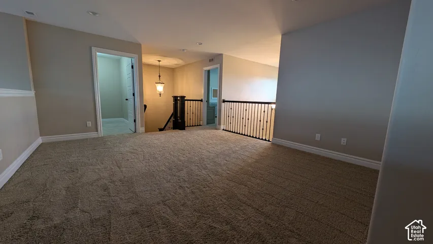 Large Carpeted loft area with recessed lighting, painted walls, white trim, and a dark wood and metal spindle railing. Great for playroom, media or game room