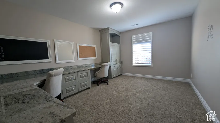 A gorgeous conveniently located upstairs office with Built-in desk with stone countertop, integrated cabinetry, and overhead storage