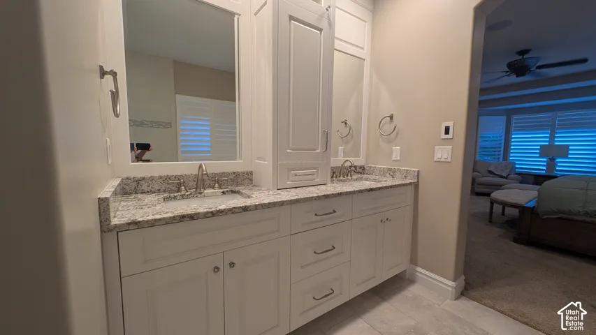 Dual basin vanity with stone countertop, white shaker cabinetry, and brushed nickel fixtures