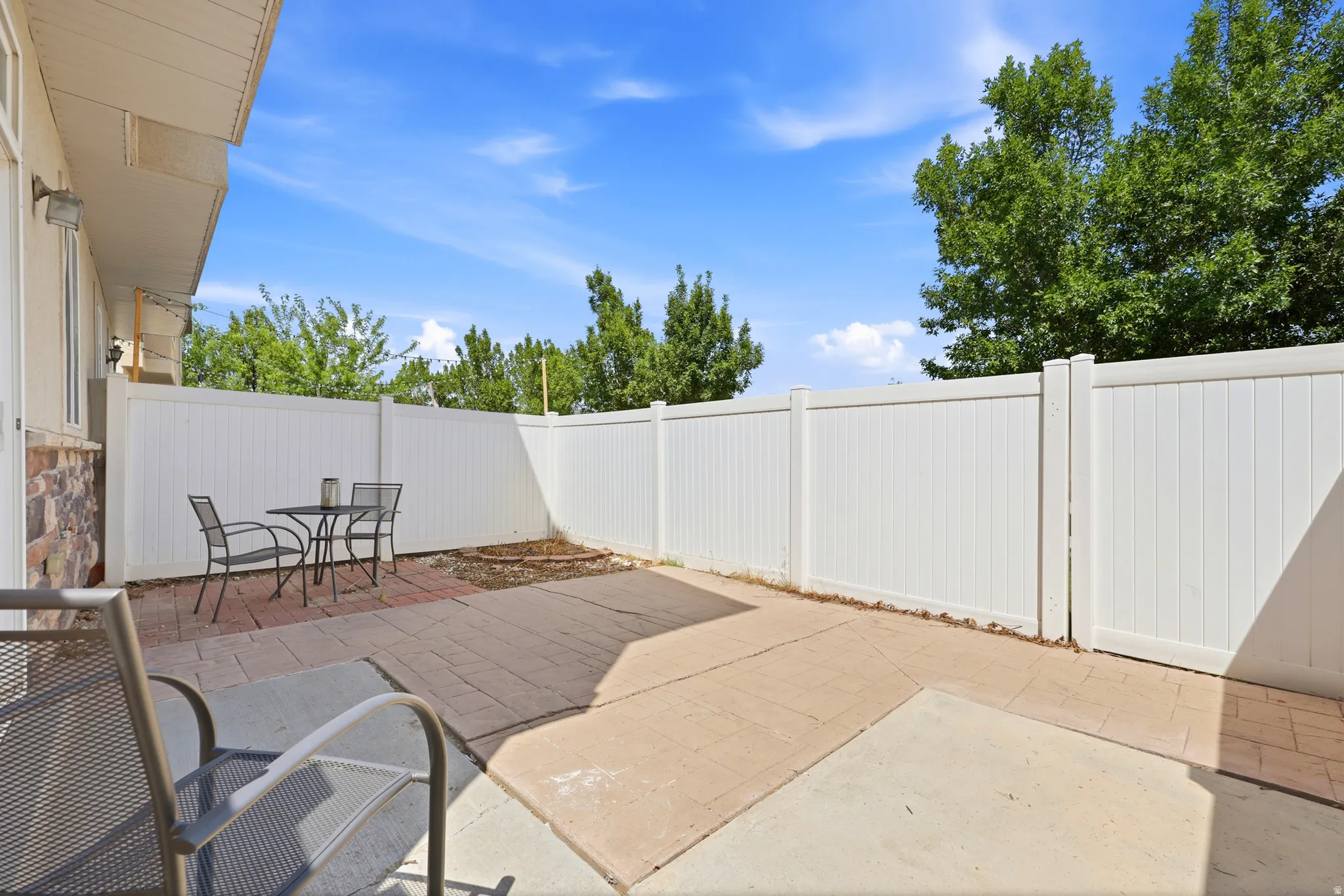 Exterior patio with mixed paving, featuring both concrete and brick-style pavers