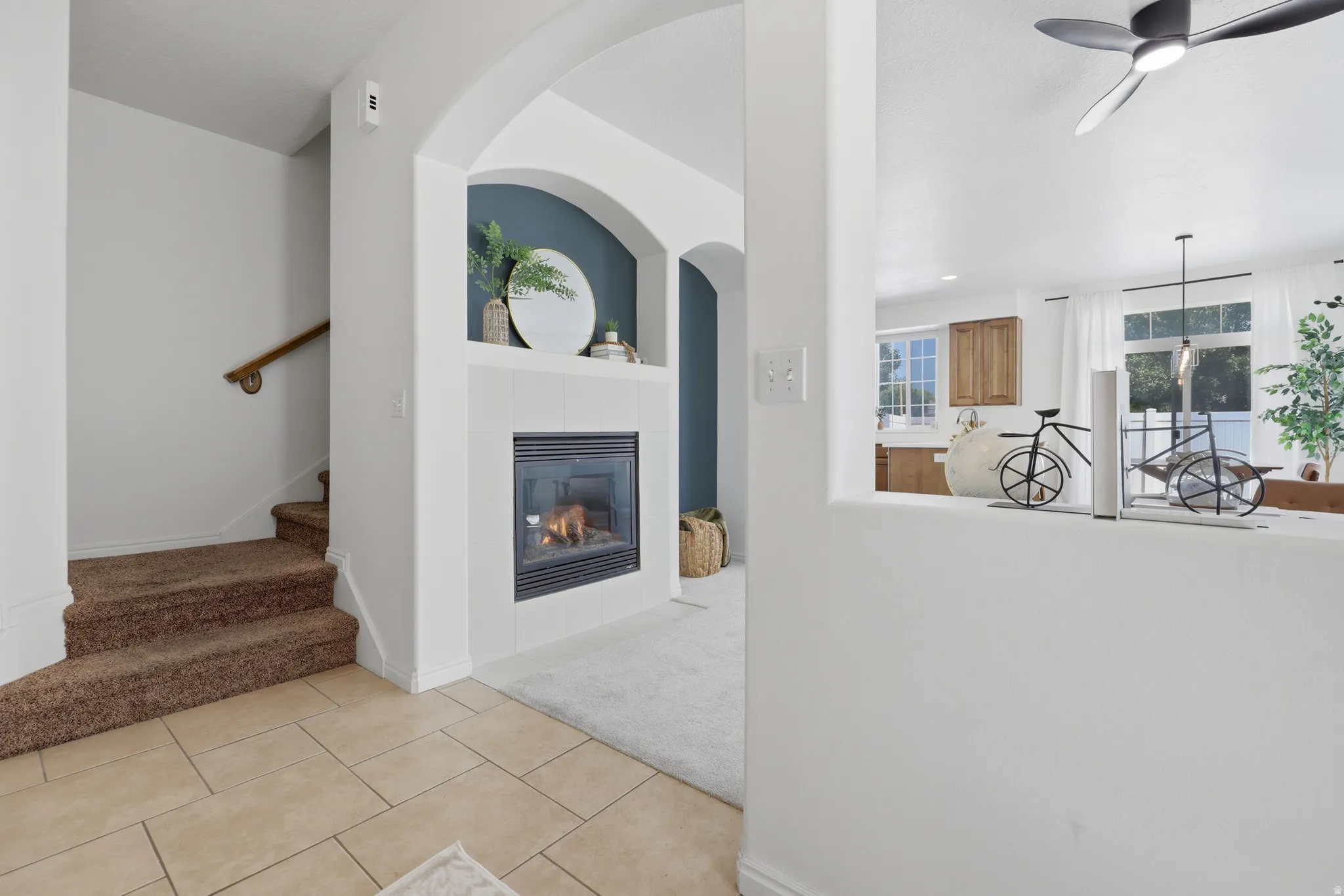Tile flooring, arched entryways, built-in fireplace, and a ceiling fan
