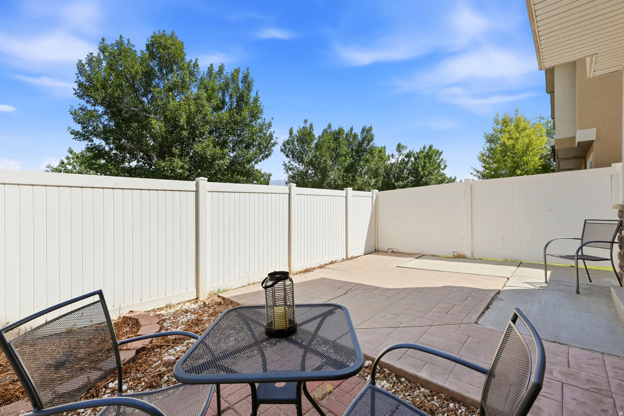 Outdoor patio area featuring a white privacy fence, stamped concrete paving, and a gravel border