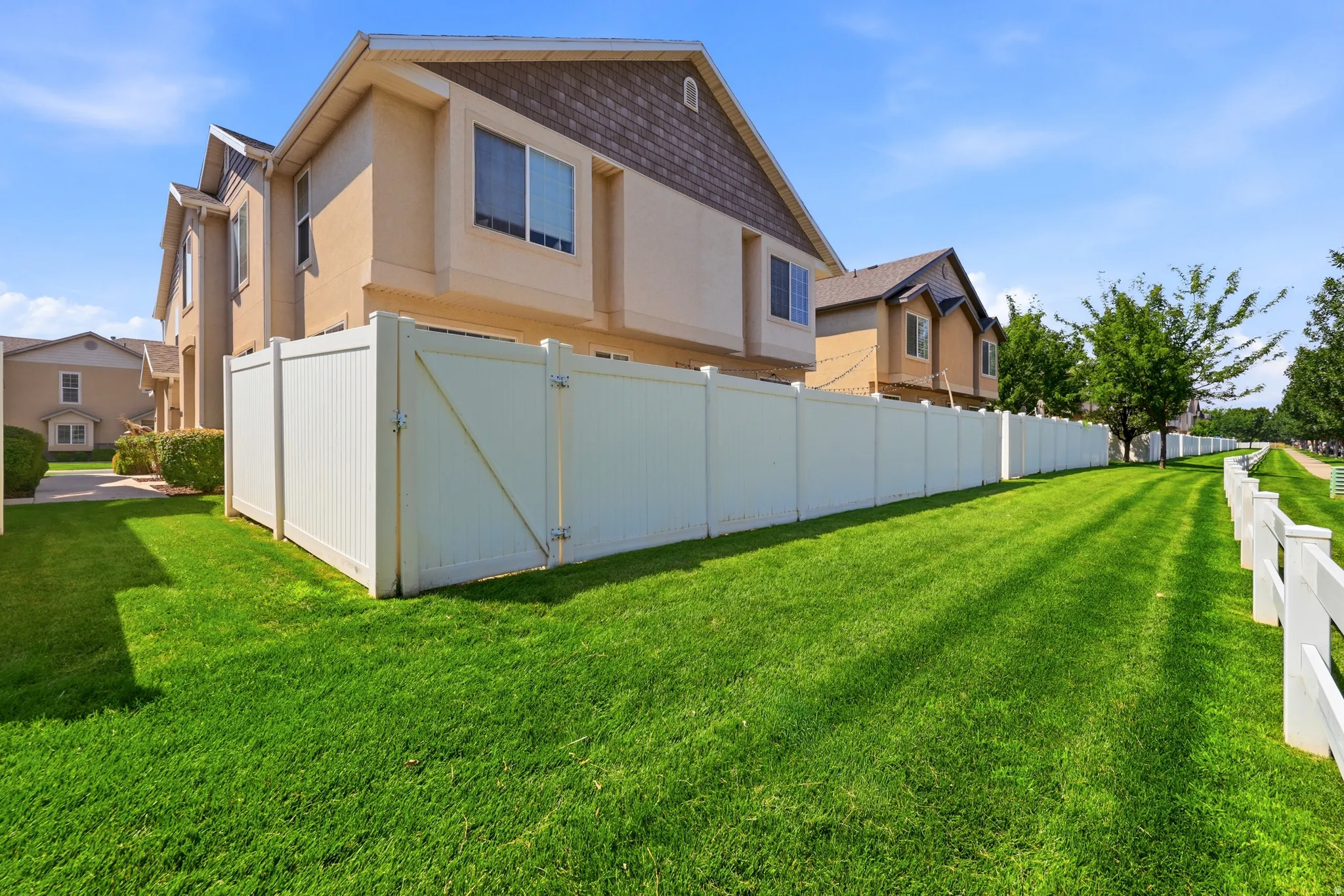 Expansive green lawn bordering a white privacy fence