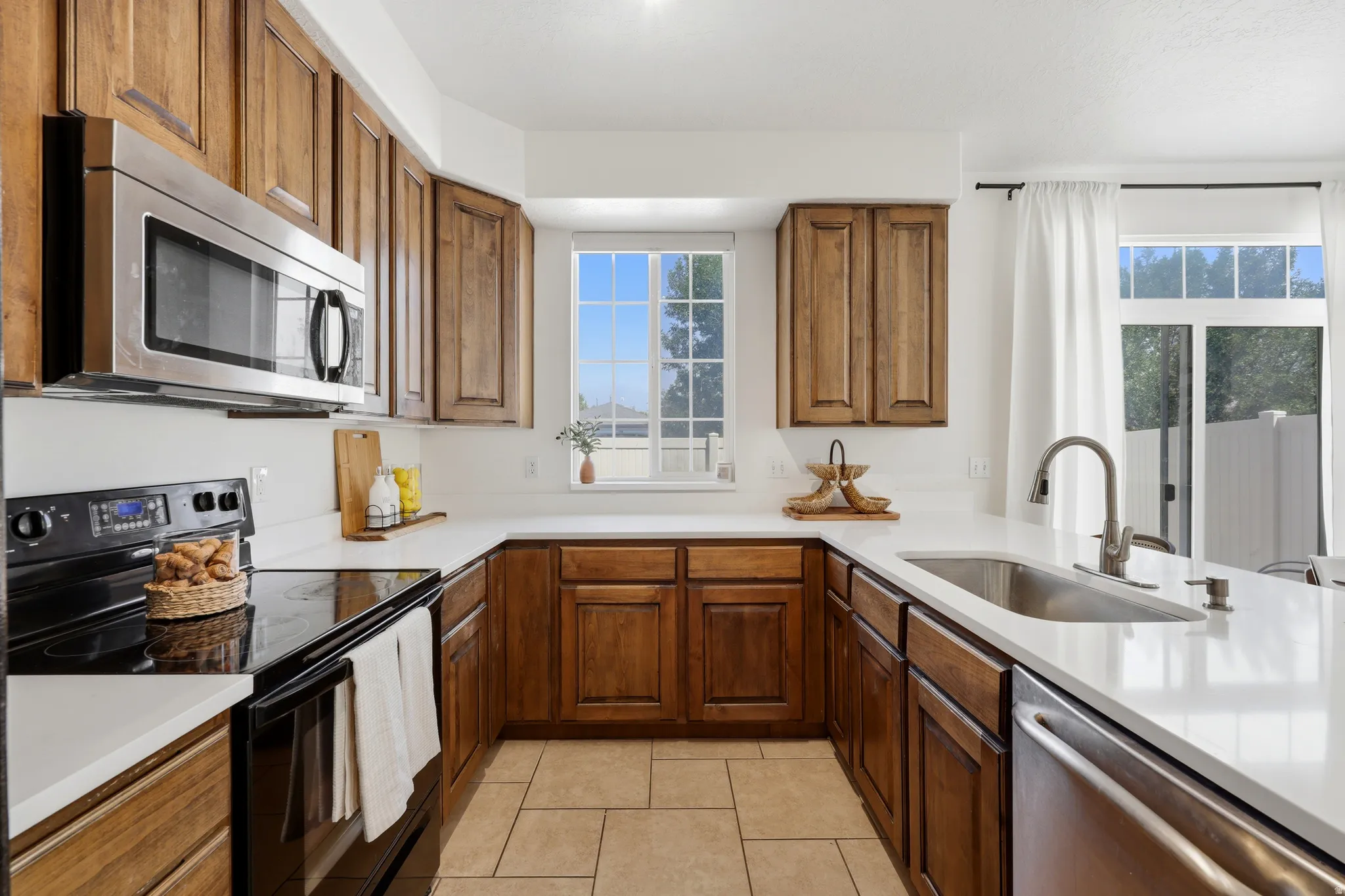 Kitchen featuring wood cabinetry, stainless steel appliances, white countertops, and tile flooring