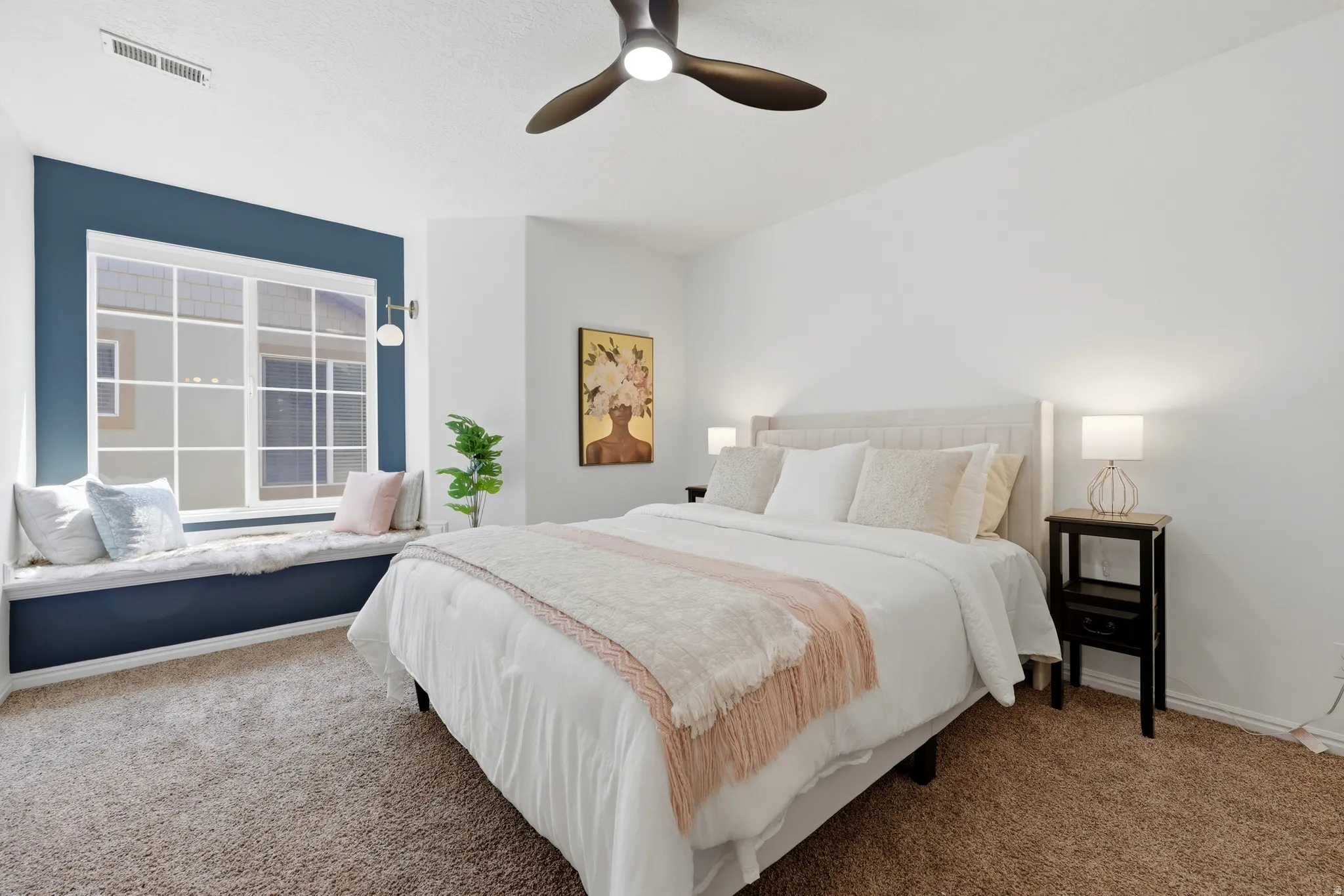 Carpeted room featuring a ceiling fan, a window with grid patterns, a built-in window seat, and sconce lighting