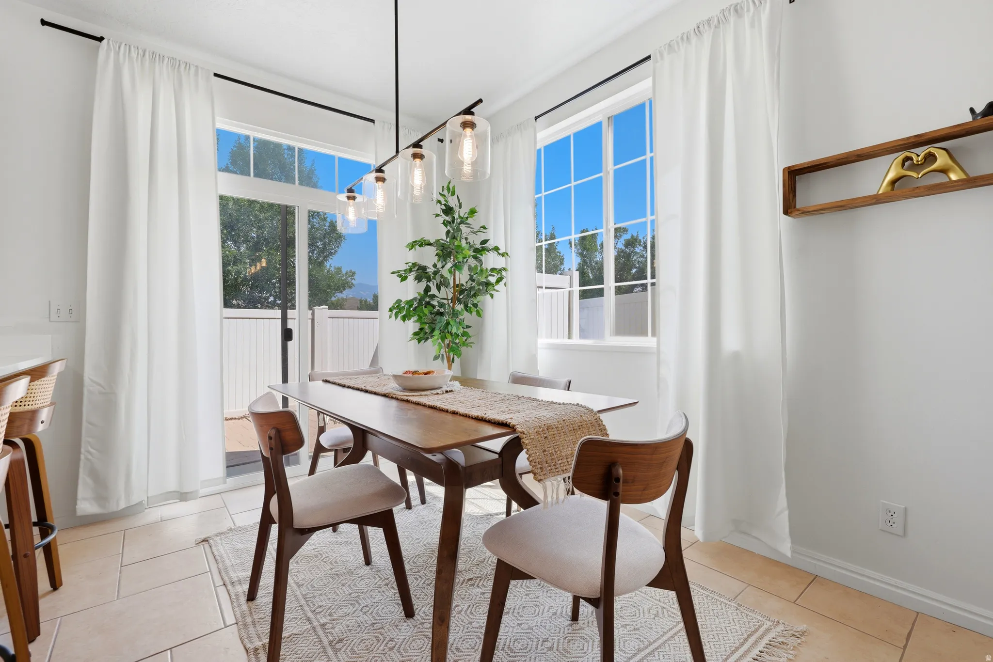Recessed lighting and a modern linear chandelier illuminate this dining area
