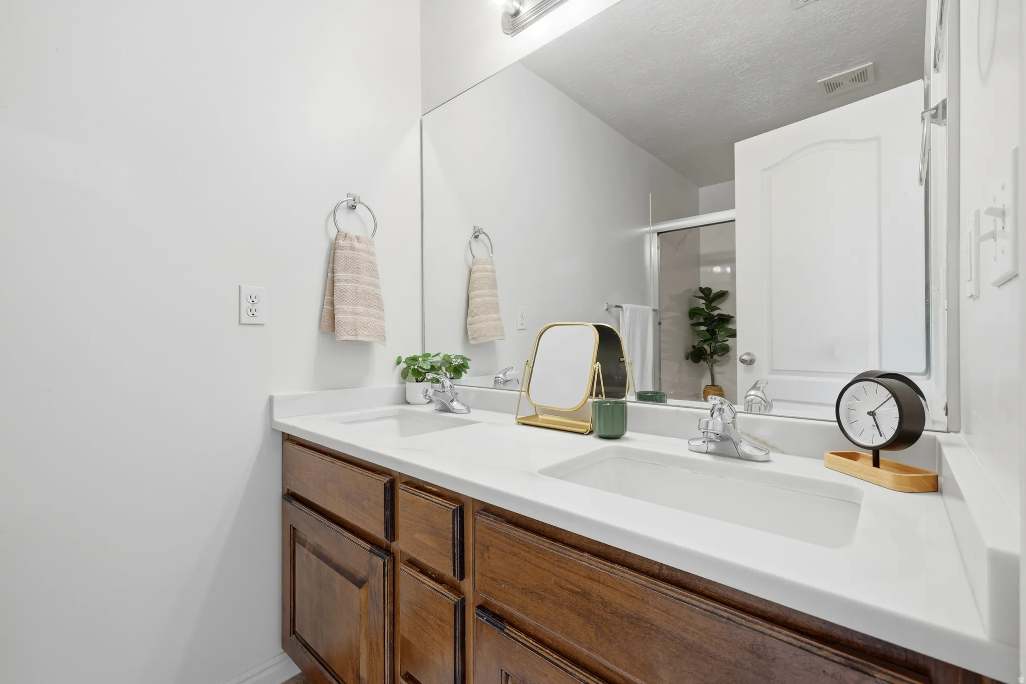Primary bath with dual vanity with wood-finish cabinetry, white countertop, and integrated sinks