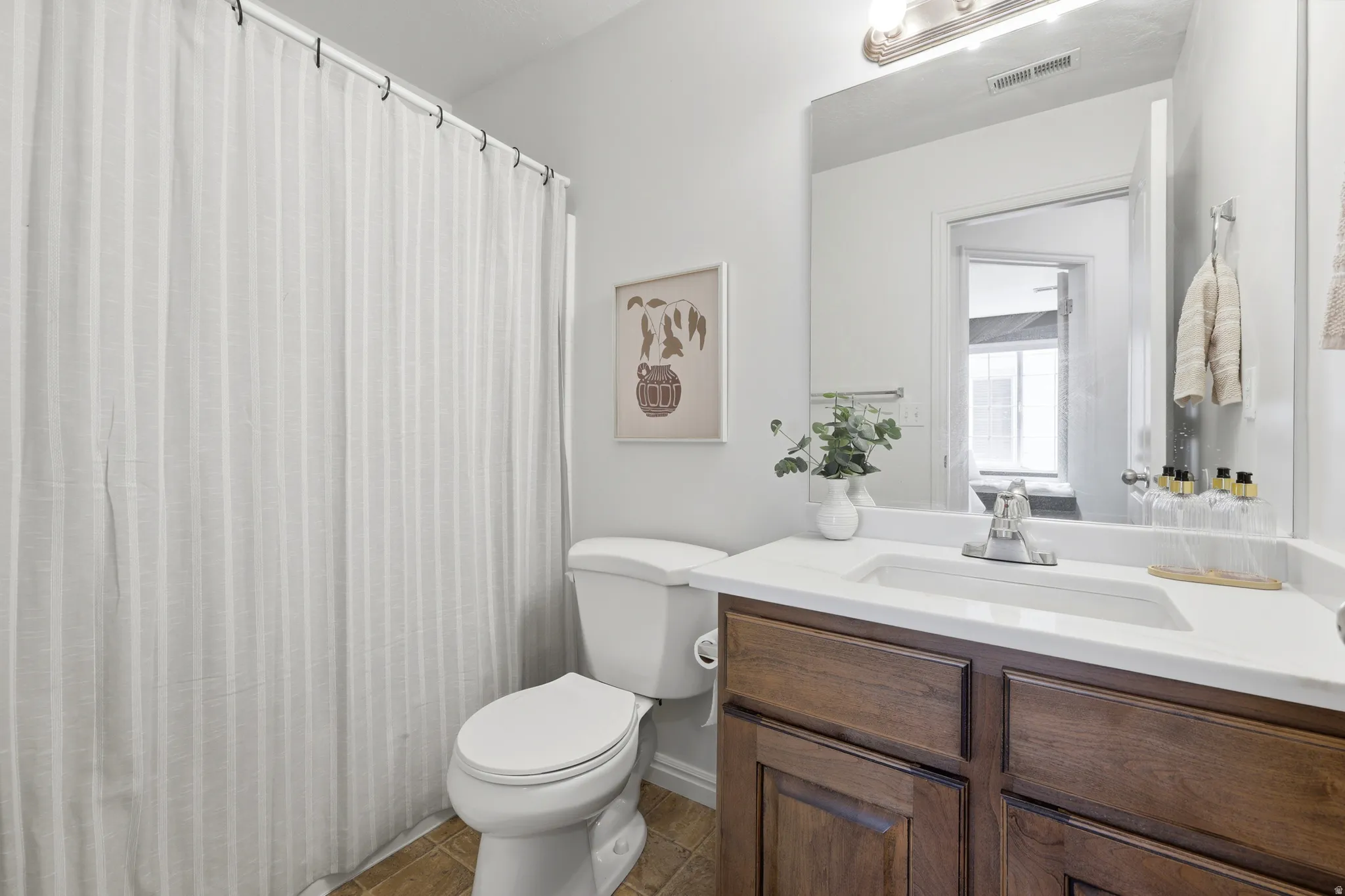 Vanity with a white countertop and integrated sink, chrome faucet, and wood-finish cabinetry