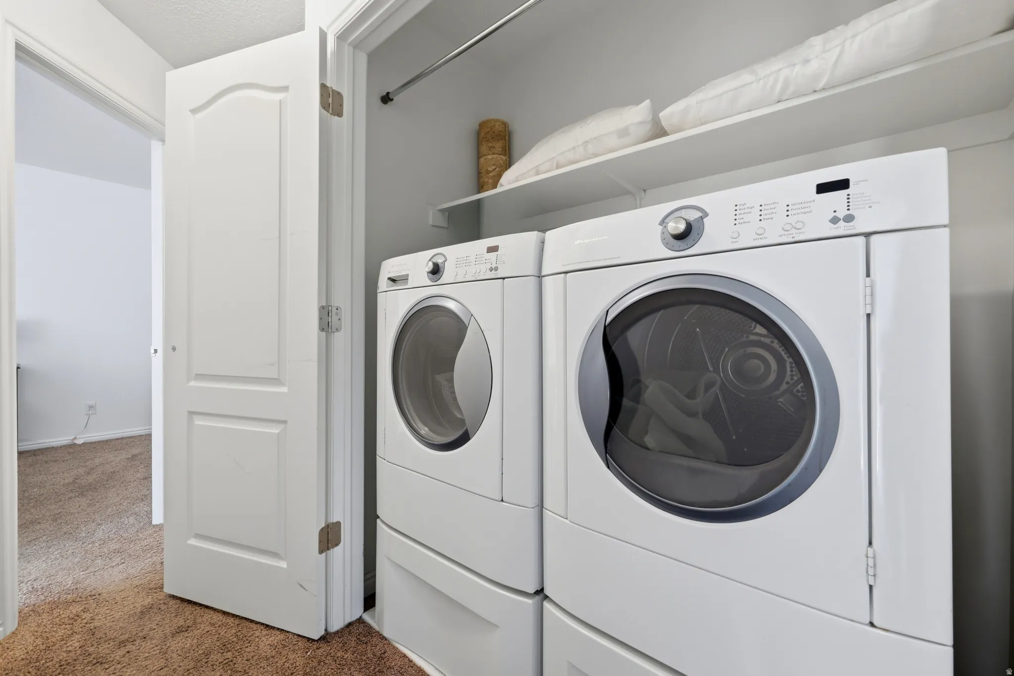 Laundry closet with white appliances, built-in shelving, and hanging rod