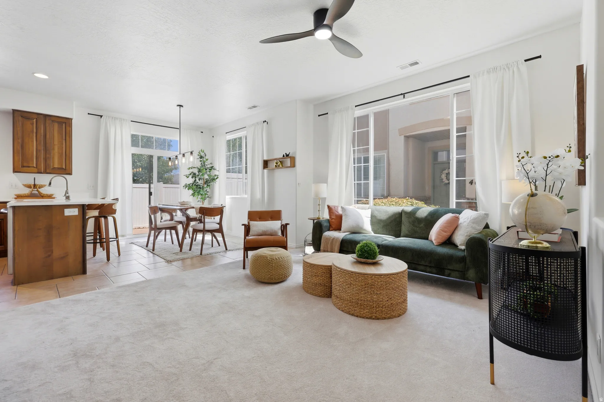 Open-concept living space featuring a ceiling fan, large windows, and an integrated dining area