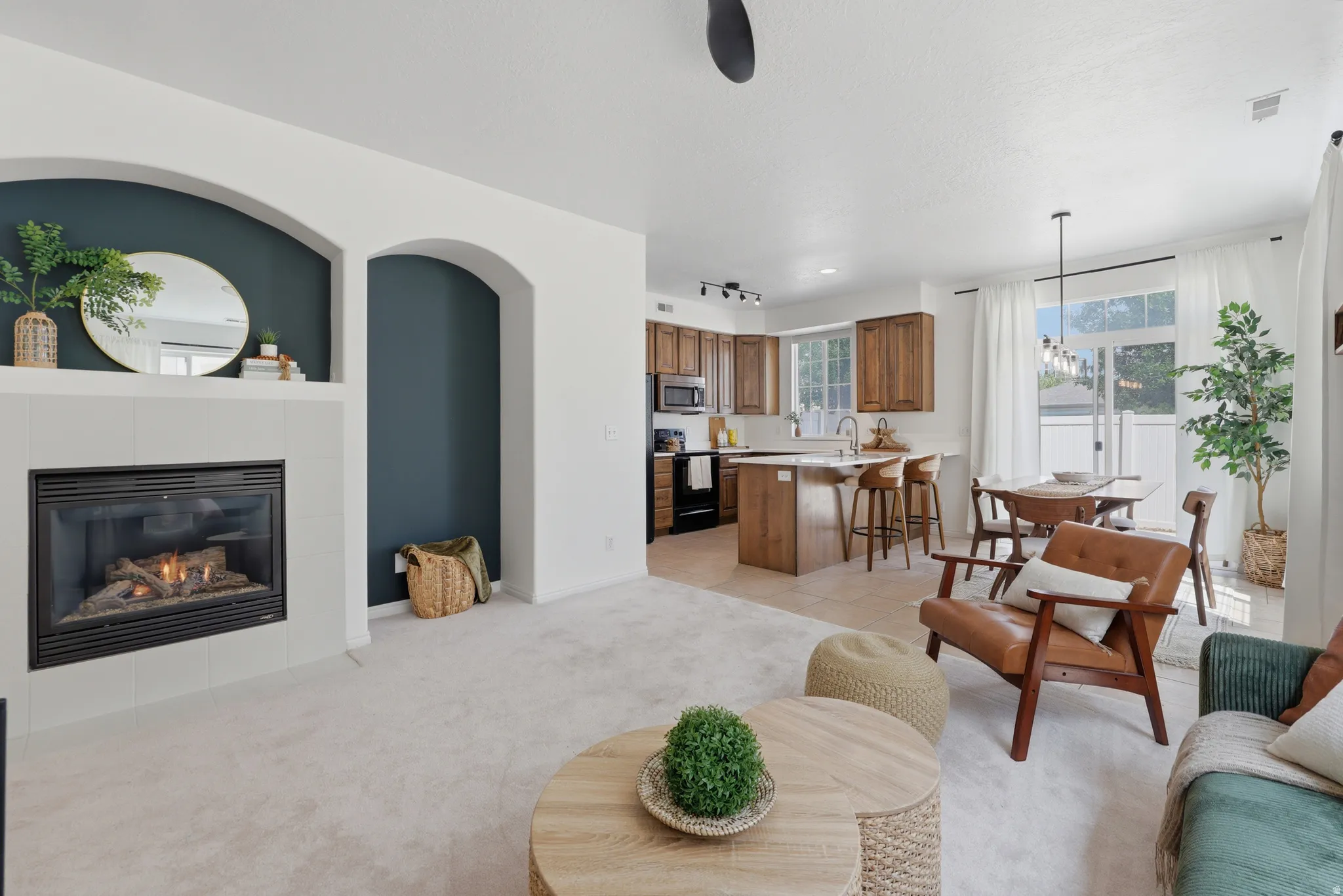 Gas fireplace with a tile surround, arched wall niches, wood cabinetry, built-in kitchen island, and a sliding glass door