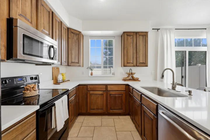 Kitchen featuring wood cabinetry, stainless steel appliances, white countertops, and tile flooring