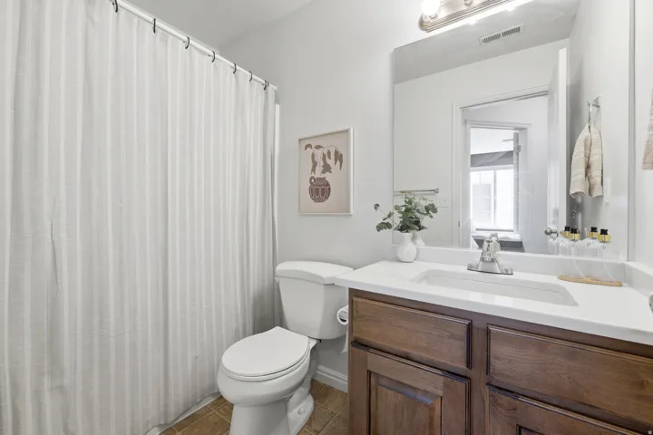 Vanity with a white countertop and integrated sink, chrome faucet, and wood-finish cabinetry