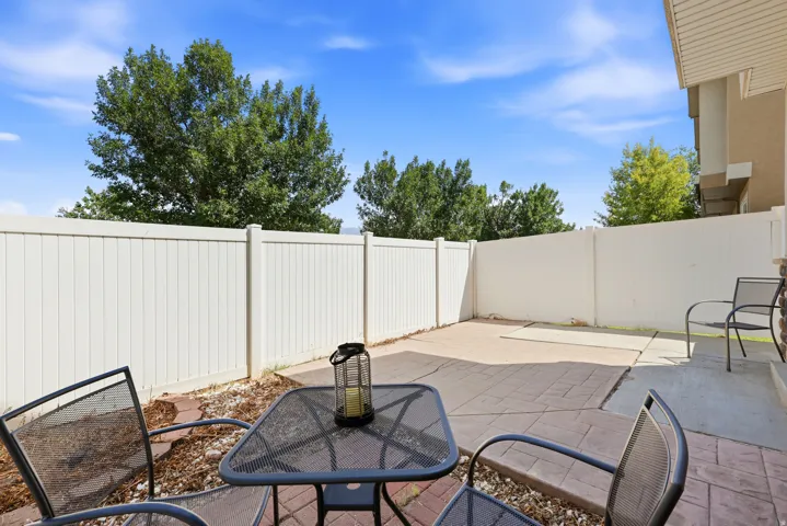 Outdoor patio area featuring a white privacy fence, stamped concrete paving, and a gravel border