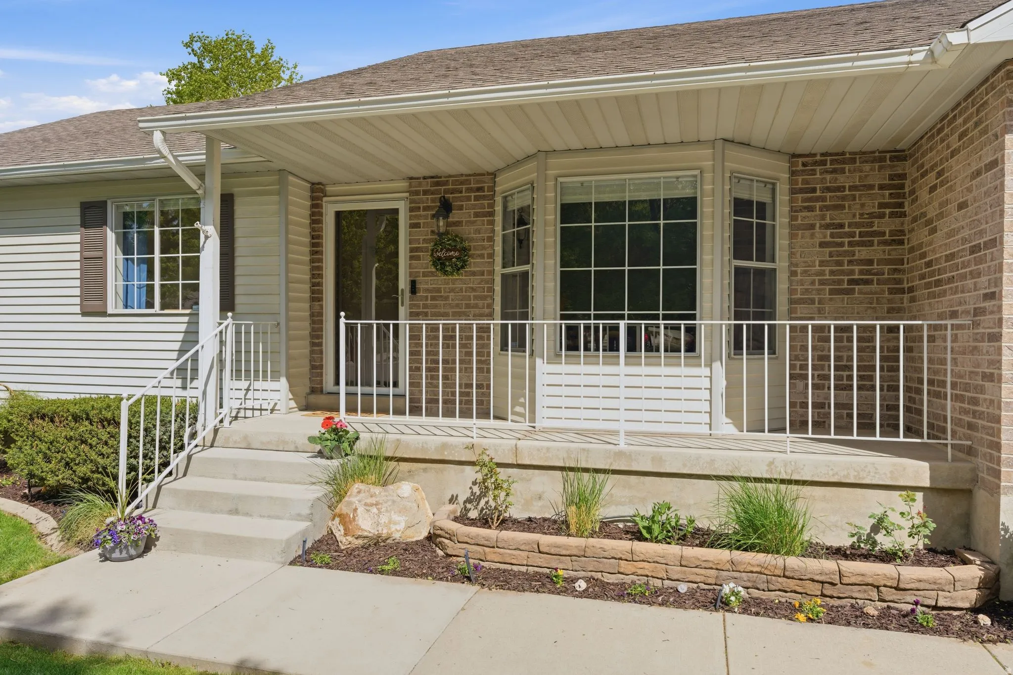 Brick and siding exterior with a covered front porch featuring white railing