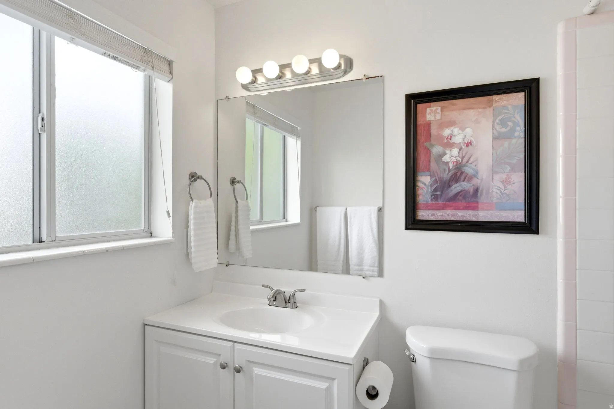 White vanity with integrated sink, chrome faucet, and white cabinetry