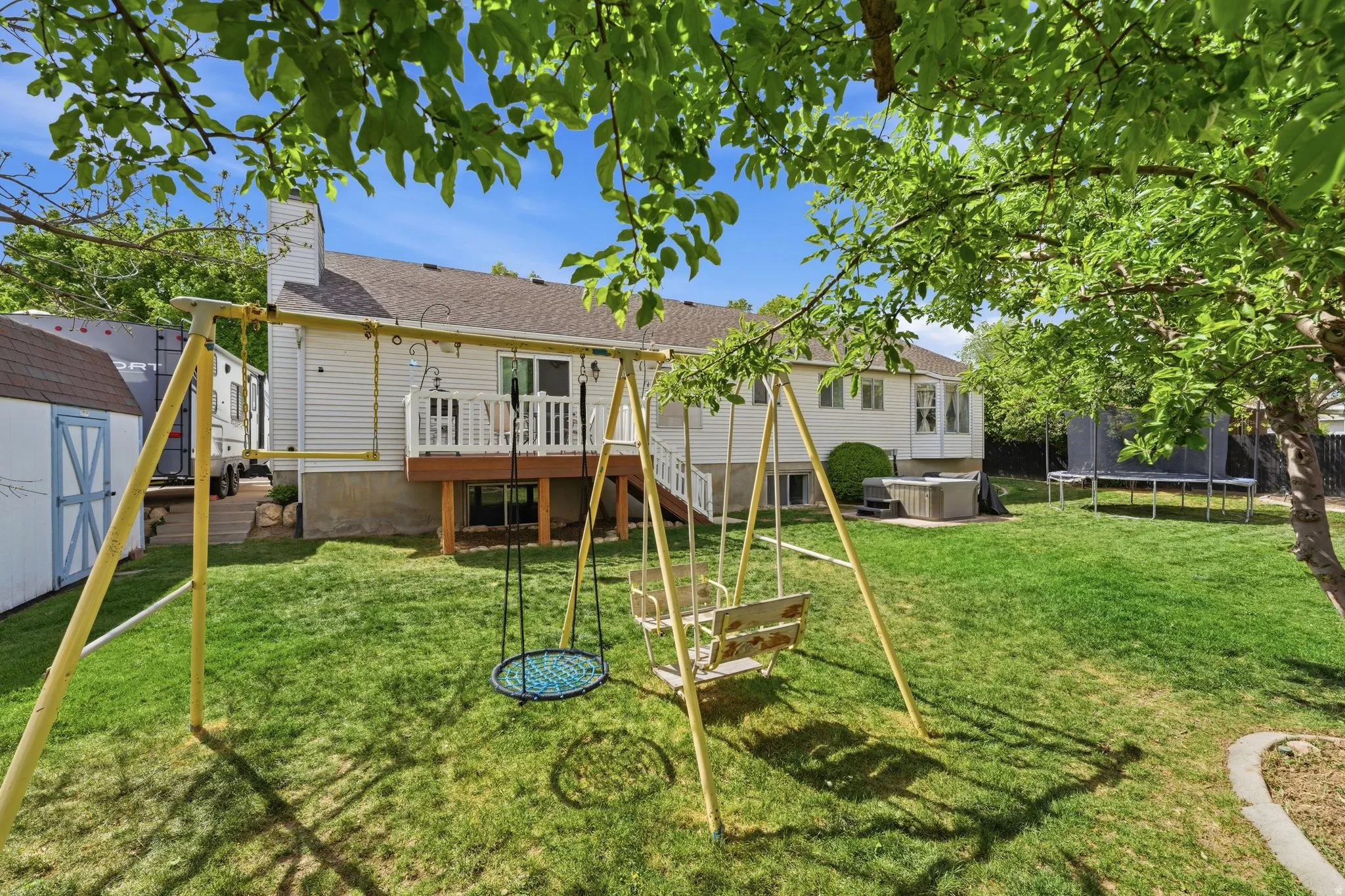 Expansive lawn area with a built-in deck, privacy fencing, and a detached storage shed