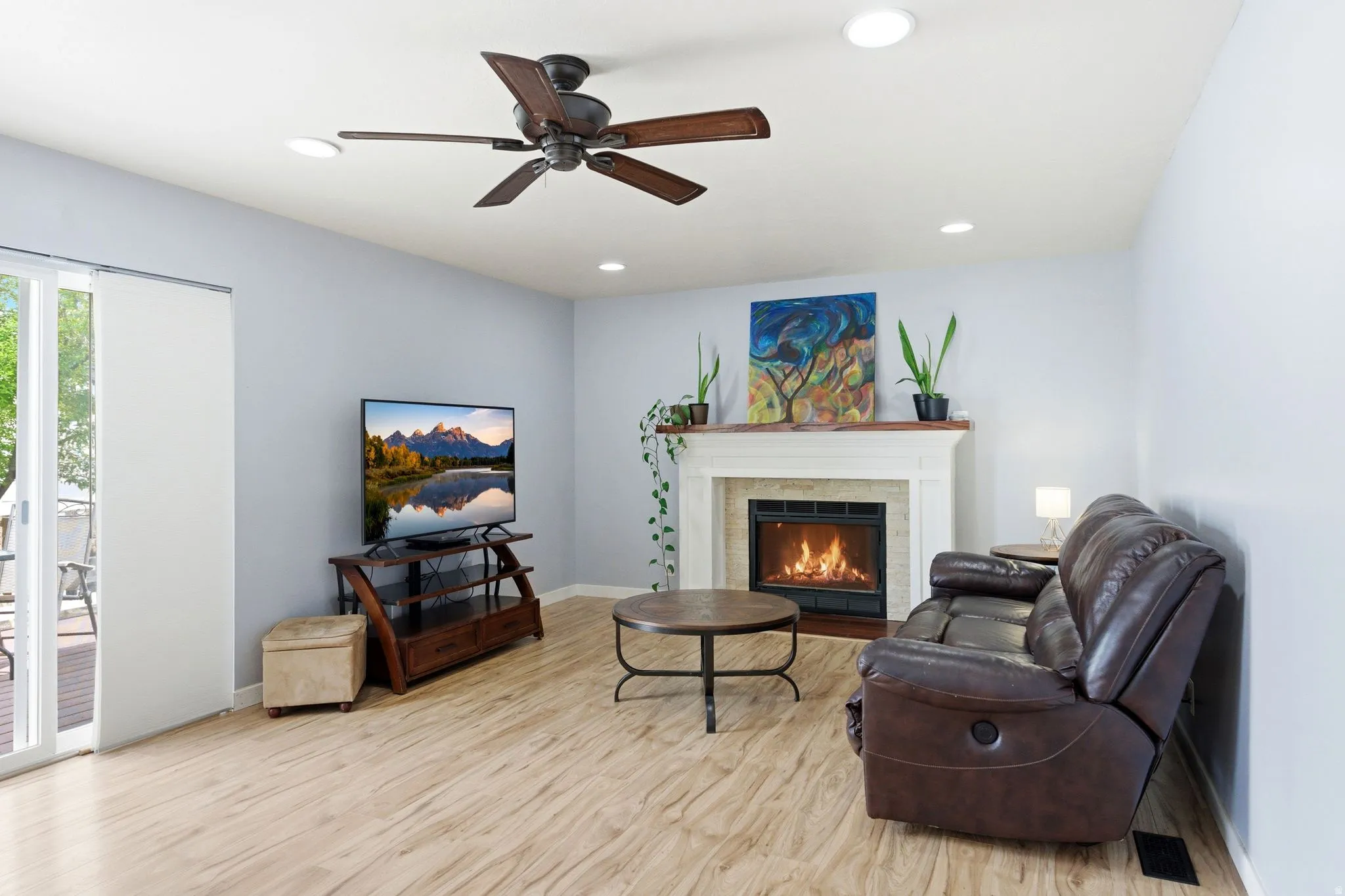 Living area featuring wood-finish flooring, a fireplace with a white mantel, recessed lighting, and a ceiling fan