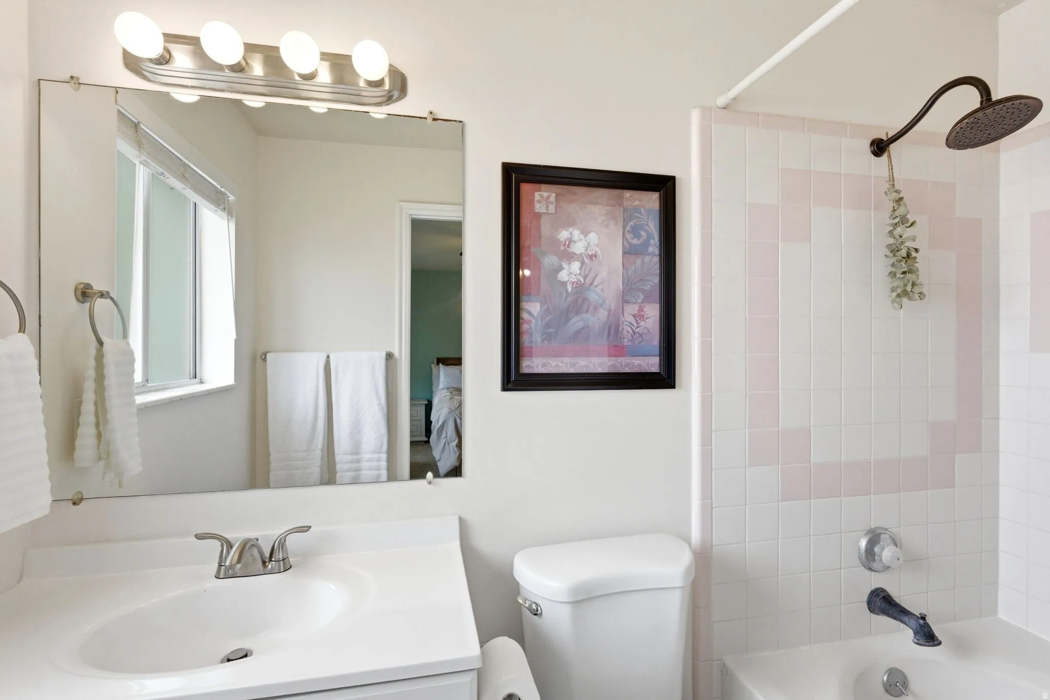 Bathroom featuring a shower/tub combination with tiled surround, a vanity with an integrated sink, a large wall-mounted mirror, and overhead vanity lighting