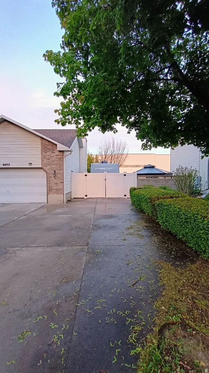 Attached two-car garage, brick and siding exterior, concrete driveway, privacy fencing, and mature landscaping