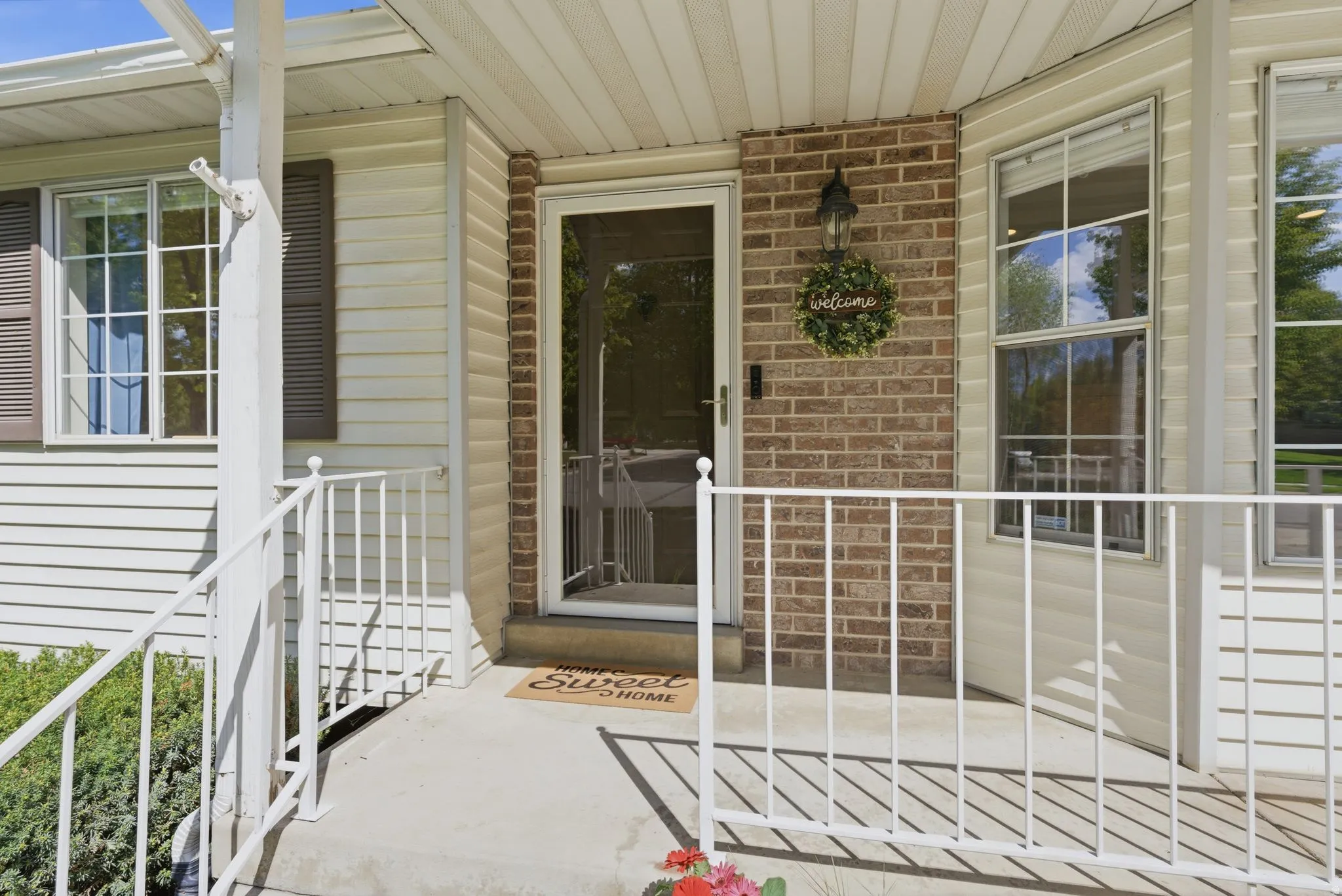Front entry with brick and siding facade, white railings, and a security screen door