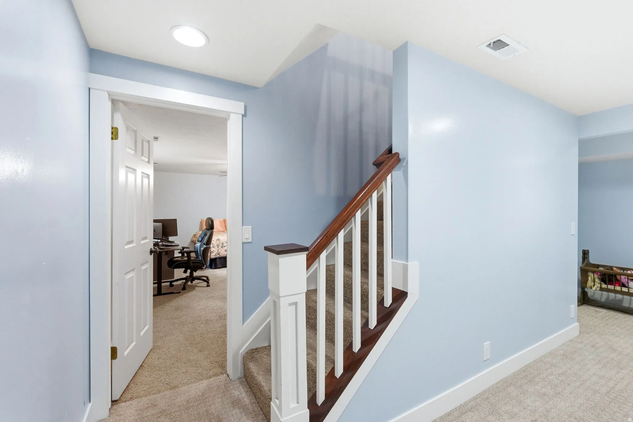 Carpeted staircase with wood-finish handrail and white balusters