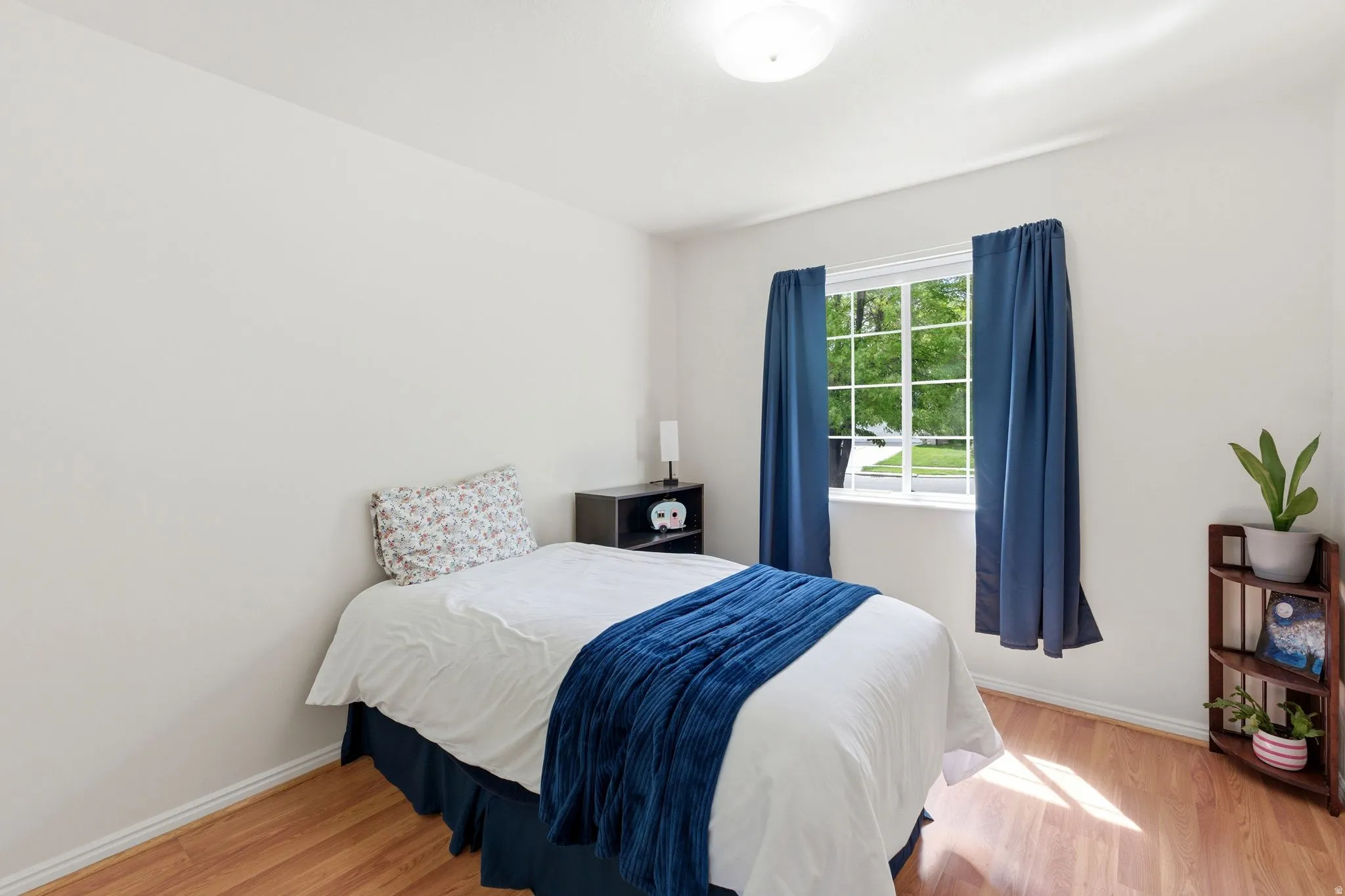 Recessed window with white frame, wood-finish flooring, white walls, and a ceiling-mounted light fixture