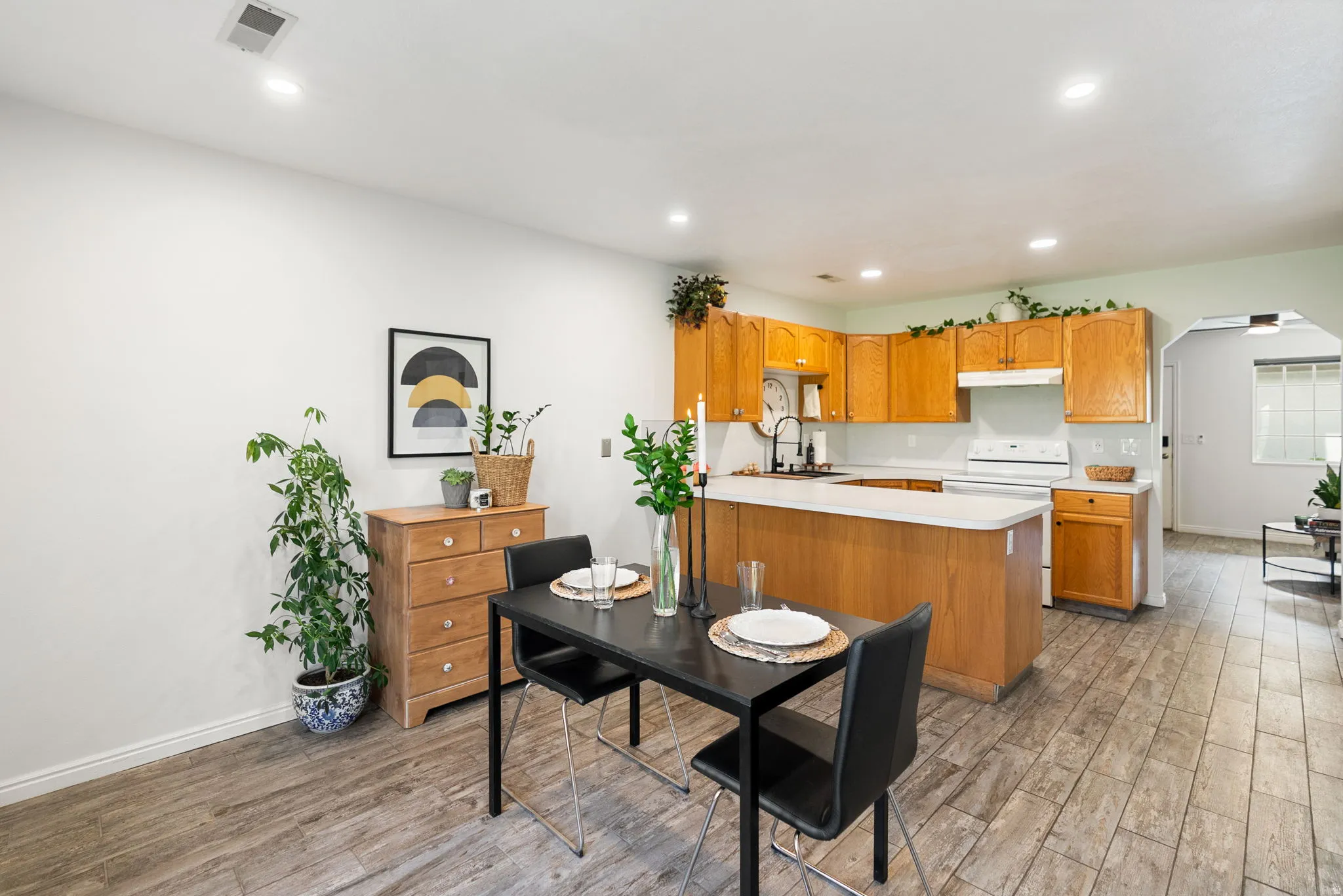 Open-concept kitchen featuring wood-finish cabinetry and white appliances, with a breakfast bar