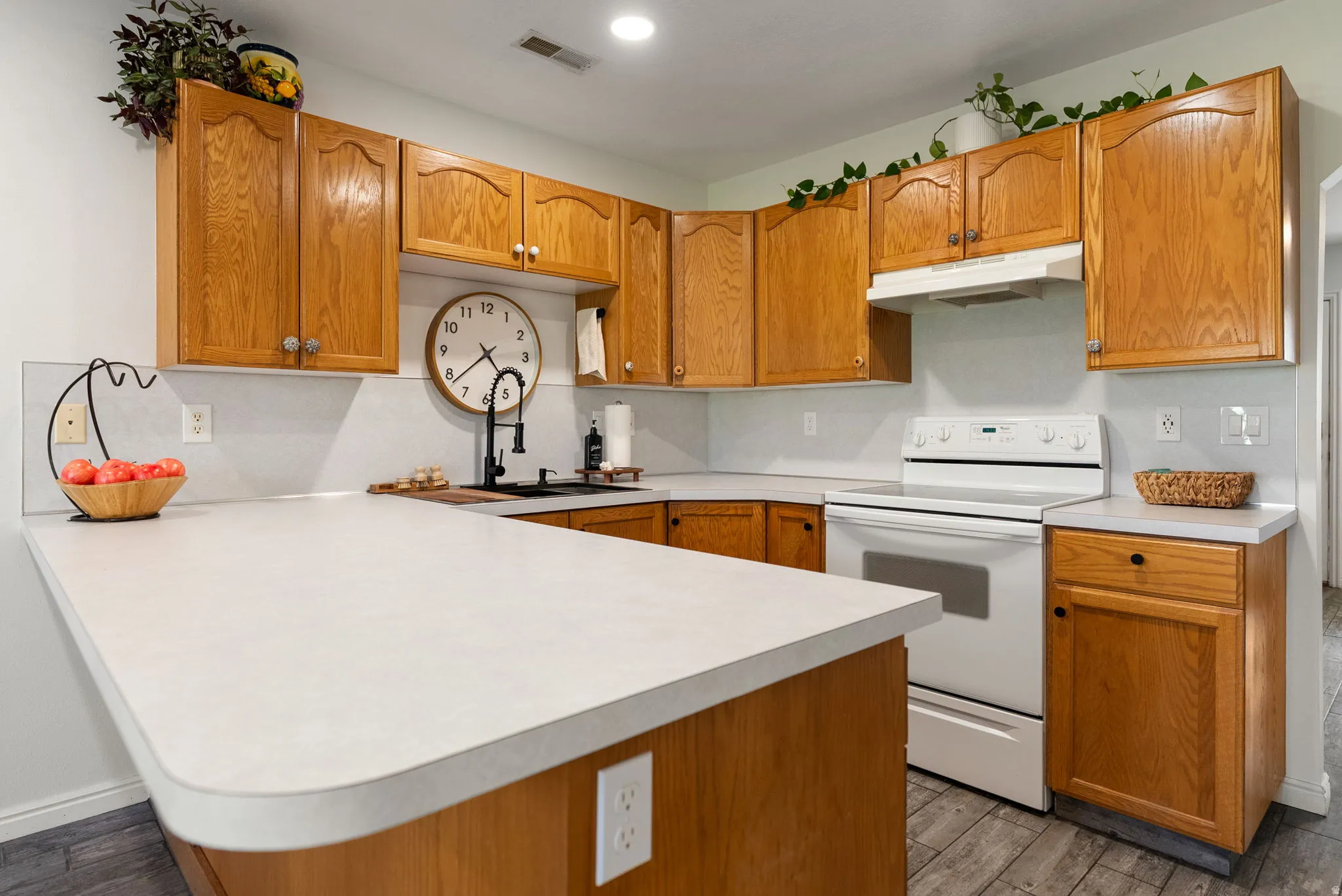 Kitchen featuring ample wood cabinetry, light-toned countertops, tile backsplash, and built-in electric range