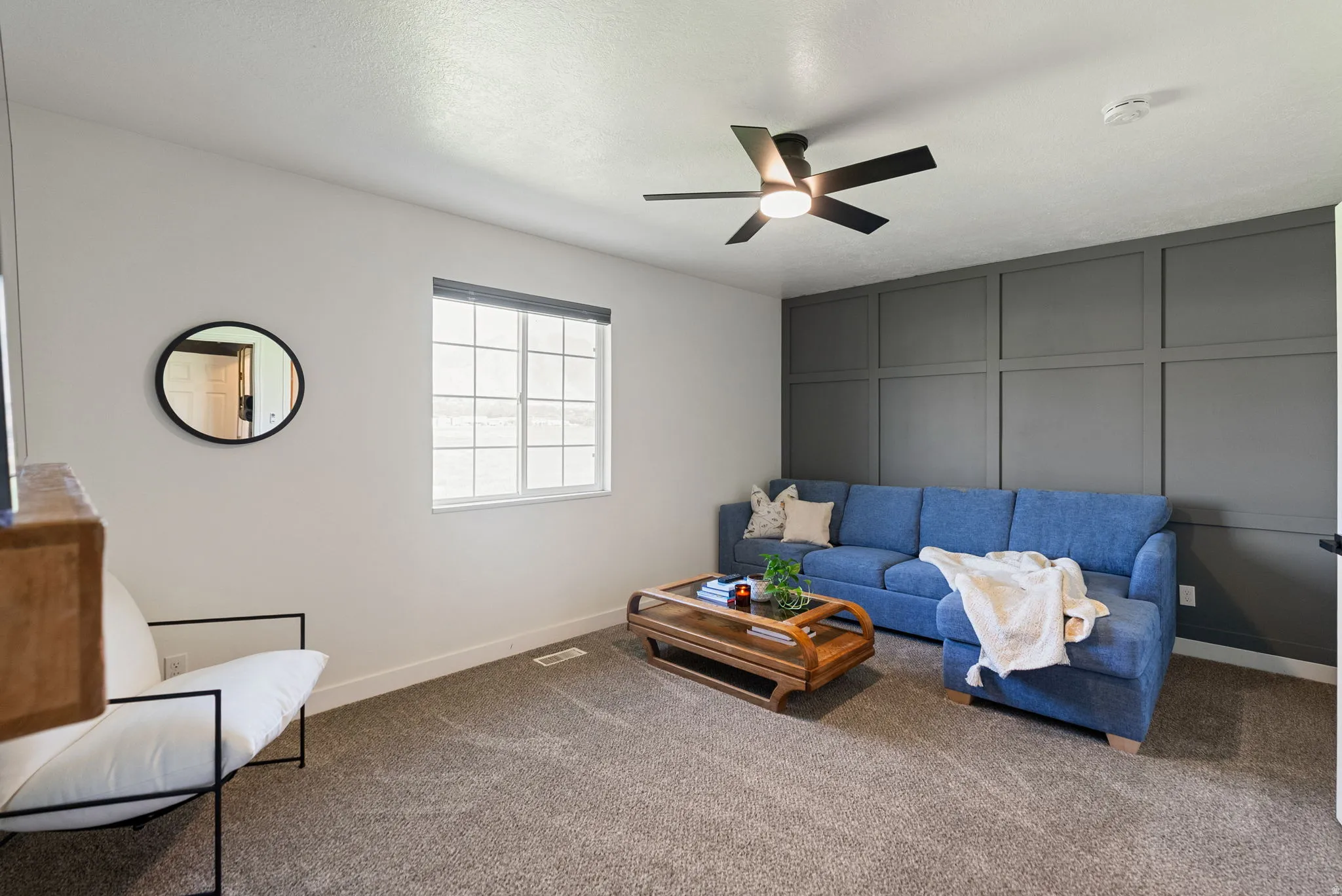 Interior space with a patterned accent wall, ceiling fan with integrated lighting, and a multi-pane window