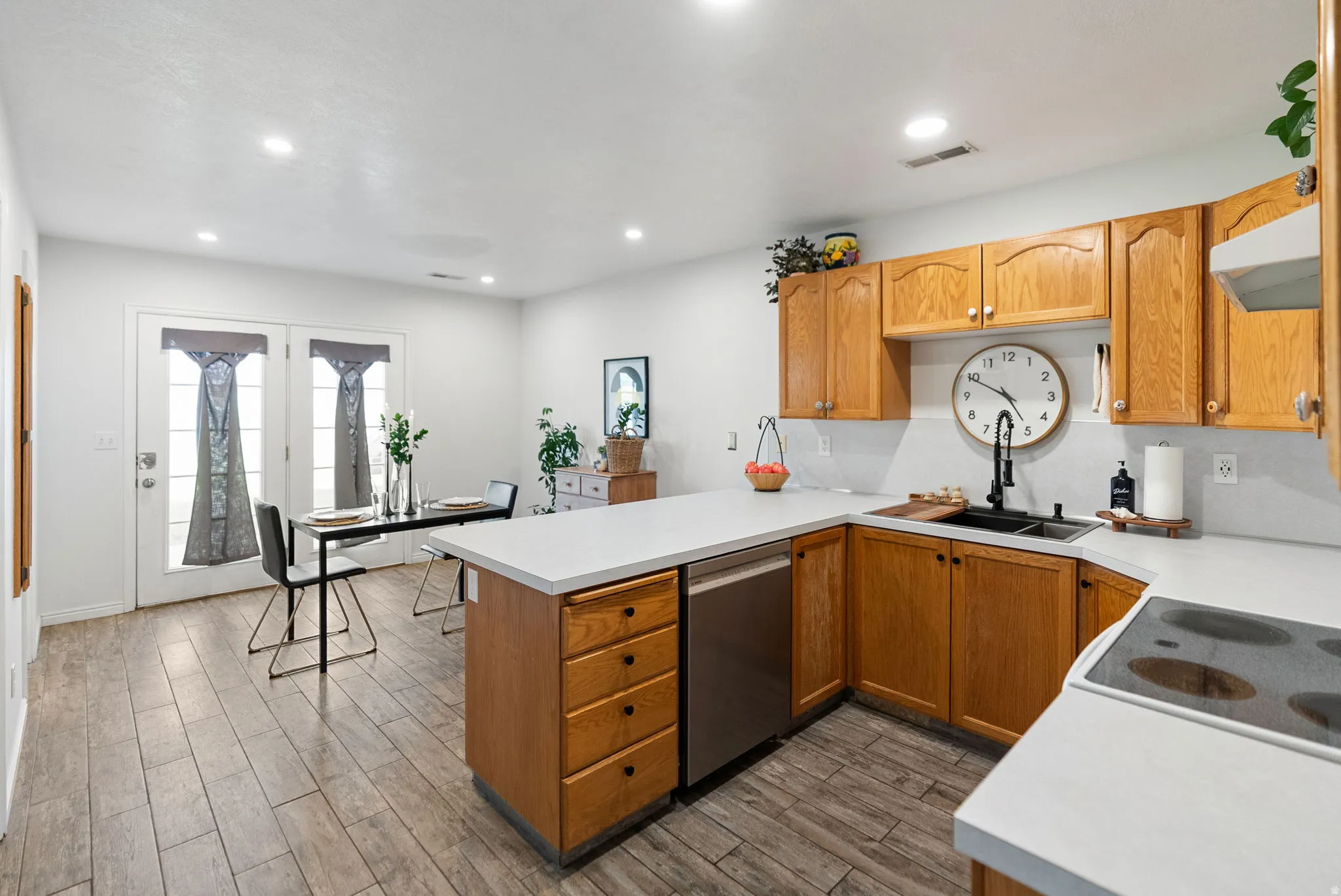 Kitchen featuring wood-finish cabinetry, white countertops, a stainless steel dishwasher, and a built-in cooktop