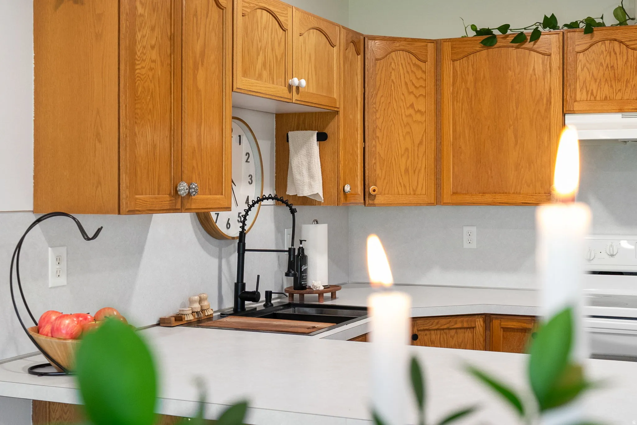 Wood cabinetry with decorative hardware, solid surface countertops, and a black gooseneck faucet
