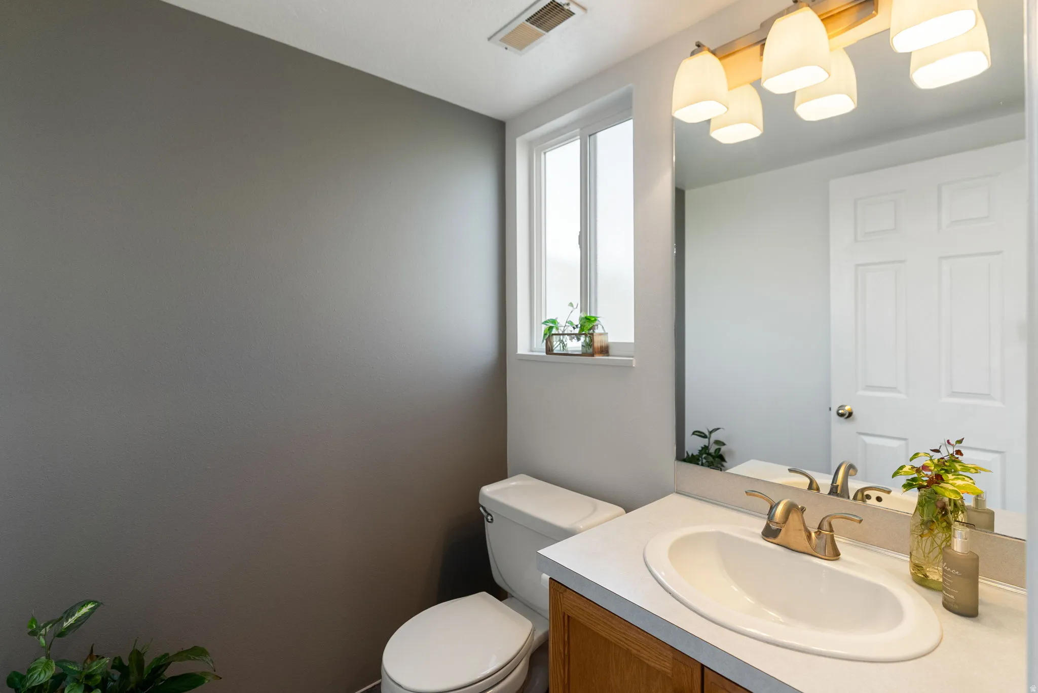 Bathroom featuring a single vanity with an integrated sink, wood-finish cabinetry, and a framed mirror