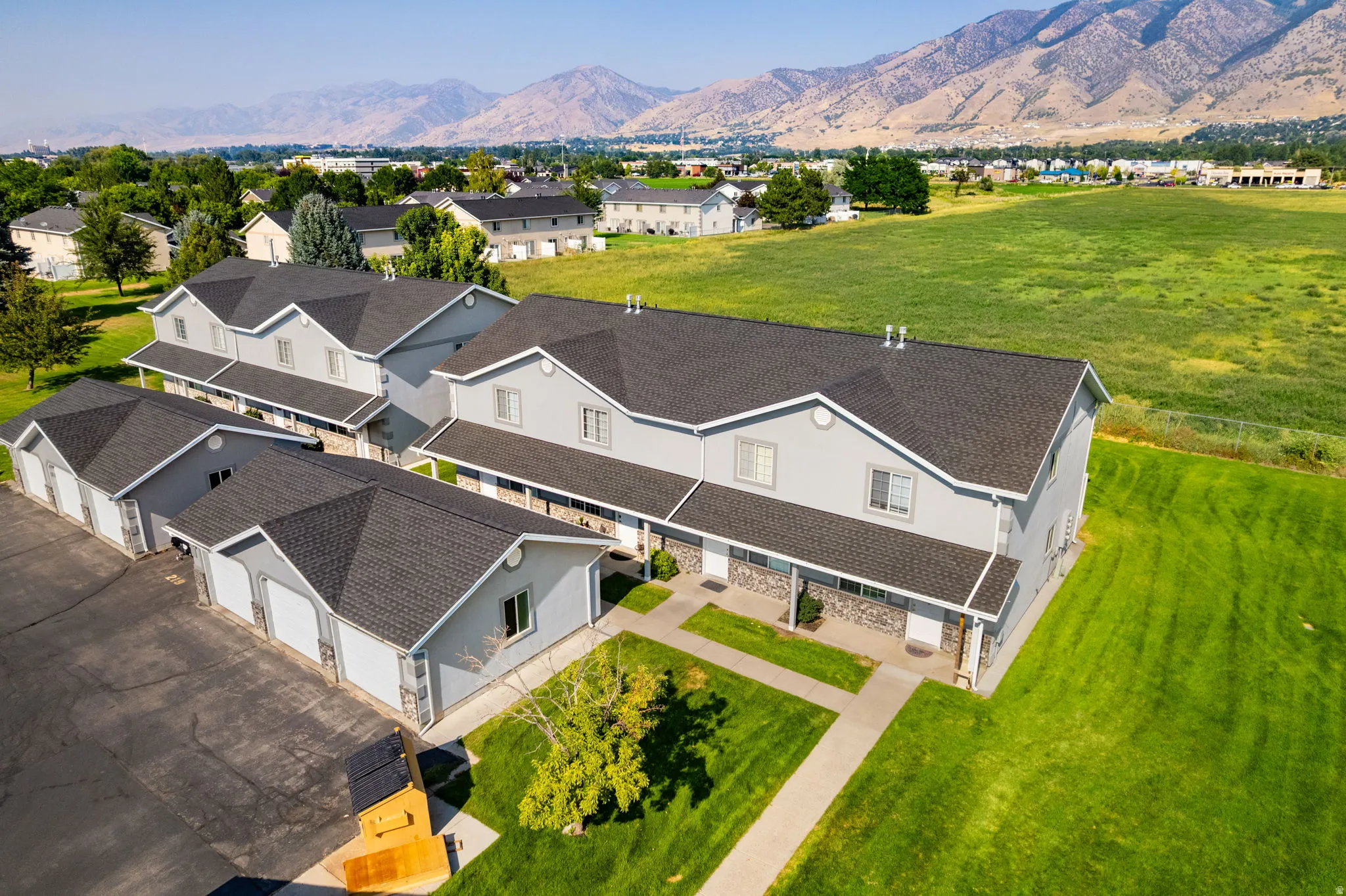 Contemporary multi-unit residence with attached garages, individual entrances, and a manicured lawn