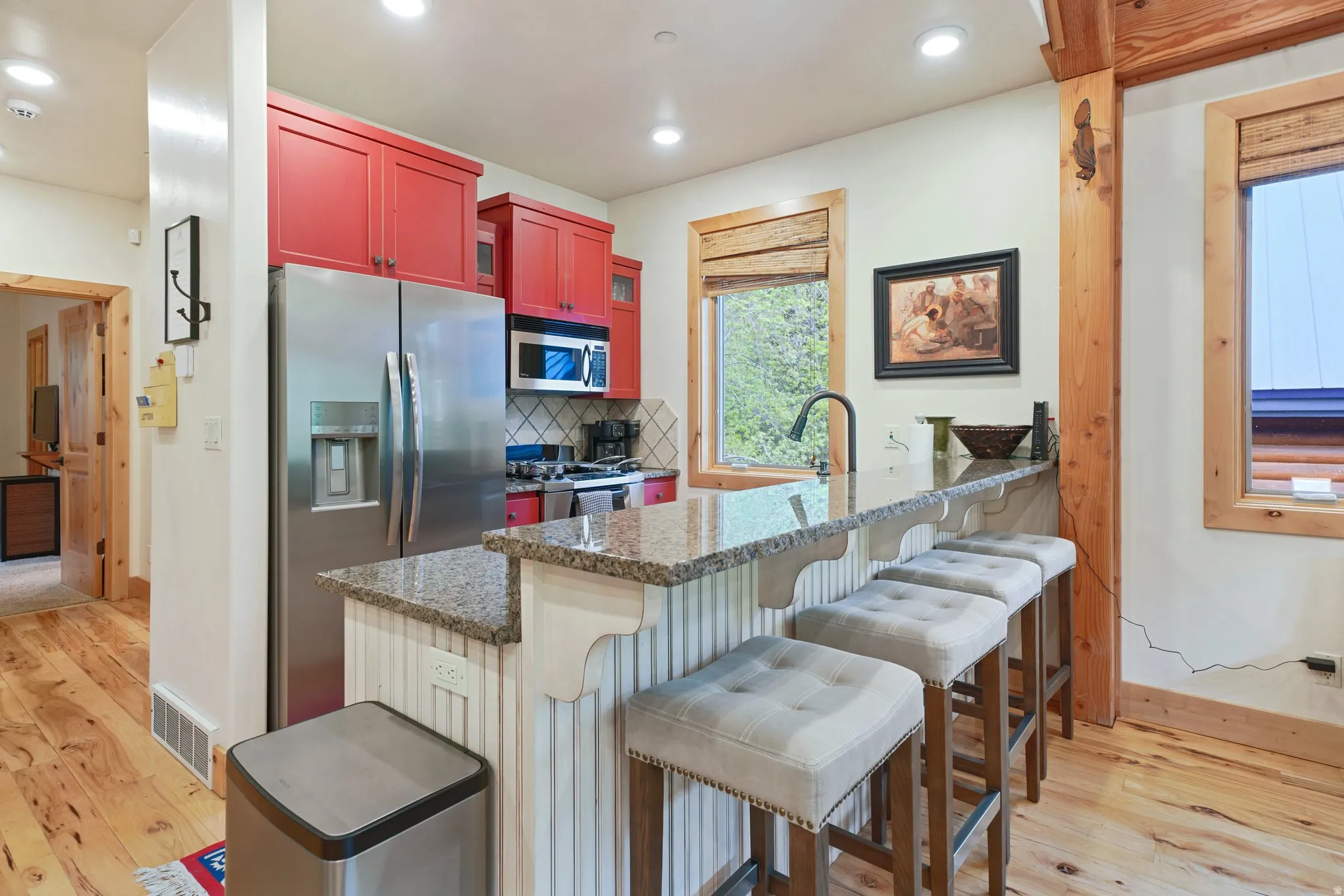Kitchen featuring stainless steel appliances, red cabinetry, and a bar-height counter with seating