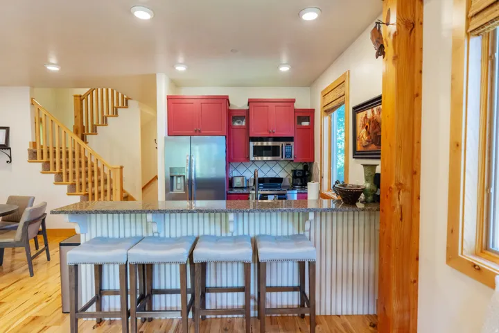 Kitchen with red cabinetry, stainless steel appliances, and a granite-look breakfast bar with beadboard paneling