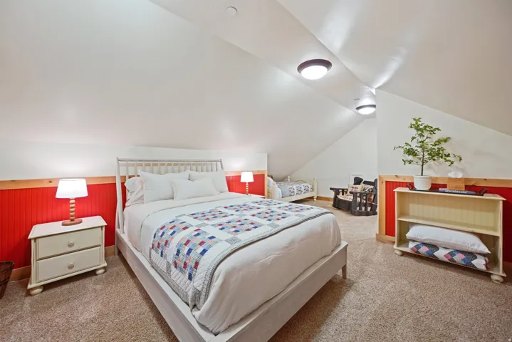 Sloped ceilings with recessed lighting, red beadboard wainscoting, light wood trim, and carpeted flooring